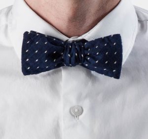 A man sporting a white shirt and a bow tie, presenting a polished and formal look.