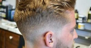 A man with a short haircut is having his hair cut by a stylist in a modern salon setting.