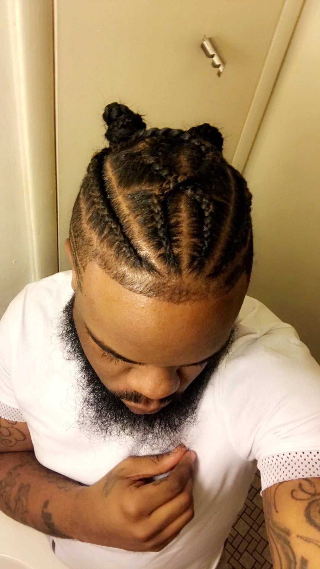 A man with a beard showcasing intricate braids in his hair, highlighting a unique and stylish braid hairstyle.