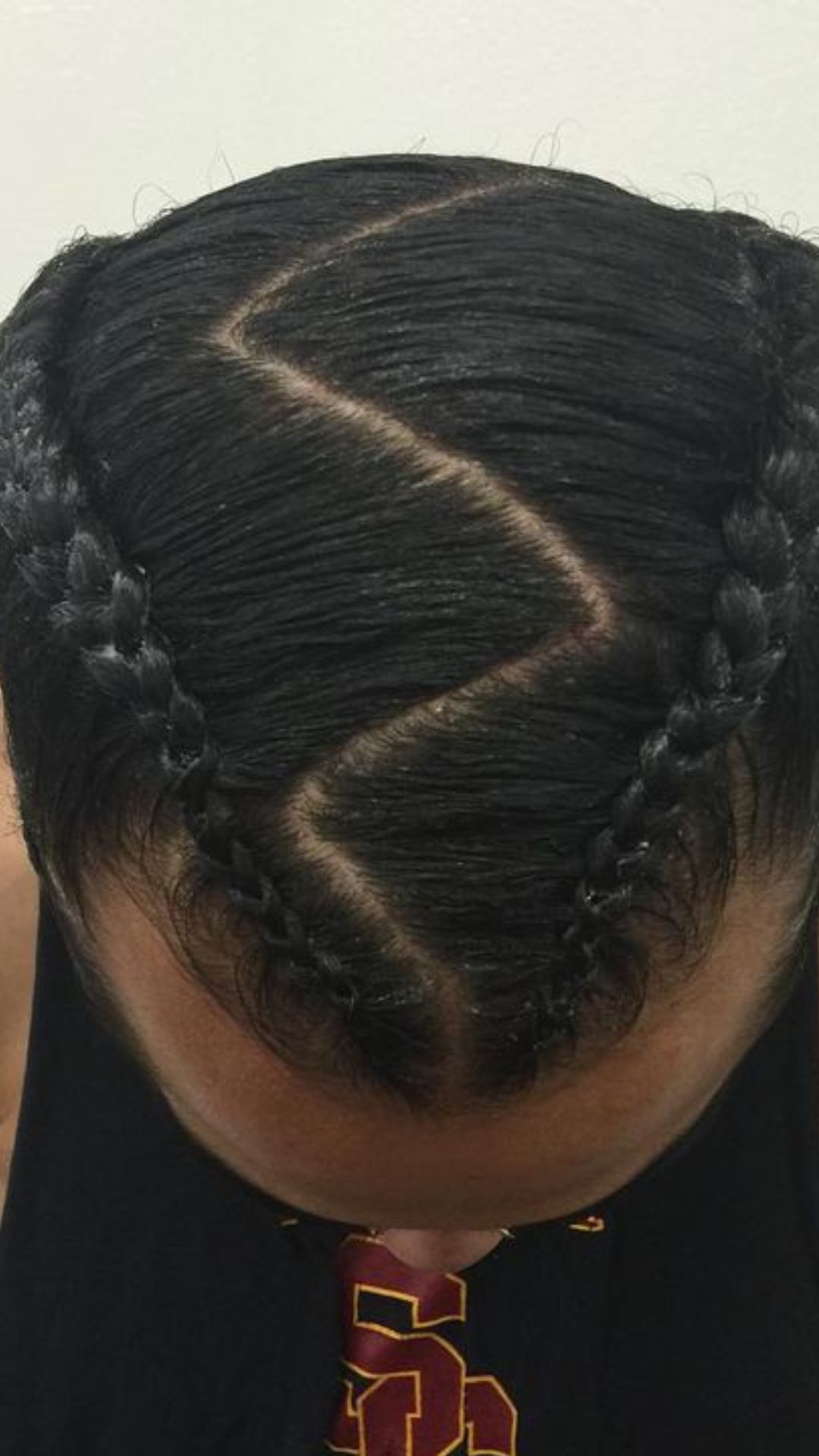 A man with an eye-catching braid hairstyle, characterized by several well-defined braids in his hair.