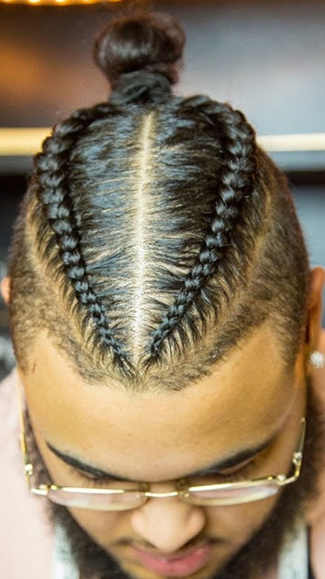 A man showcasing a stylish braided hairstyle, highlighting the intricate design and texture of the braids.