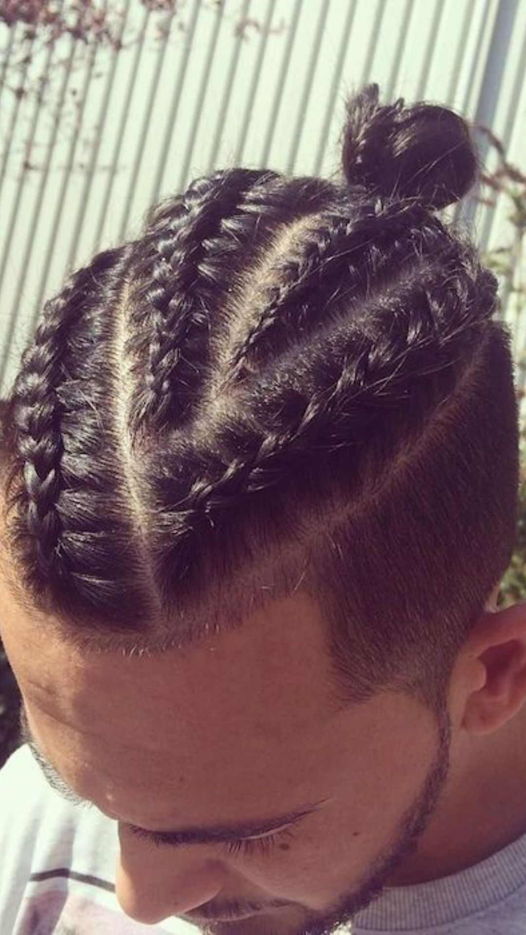 A man sporting a braided bun, demonstrating a fashionable and contemporary approach to braid hairstyles.