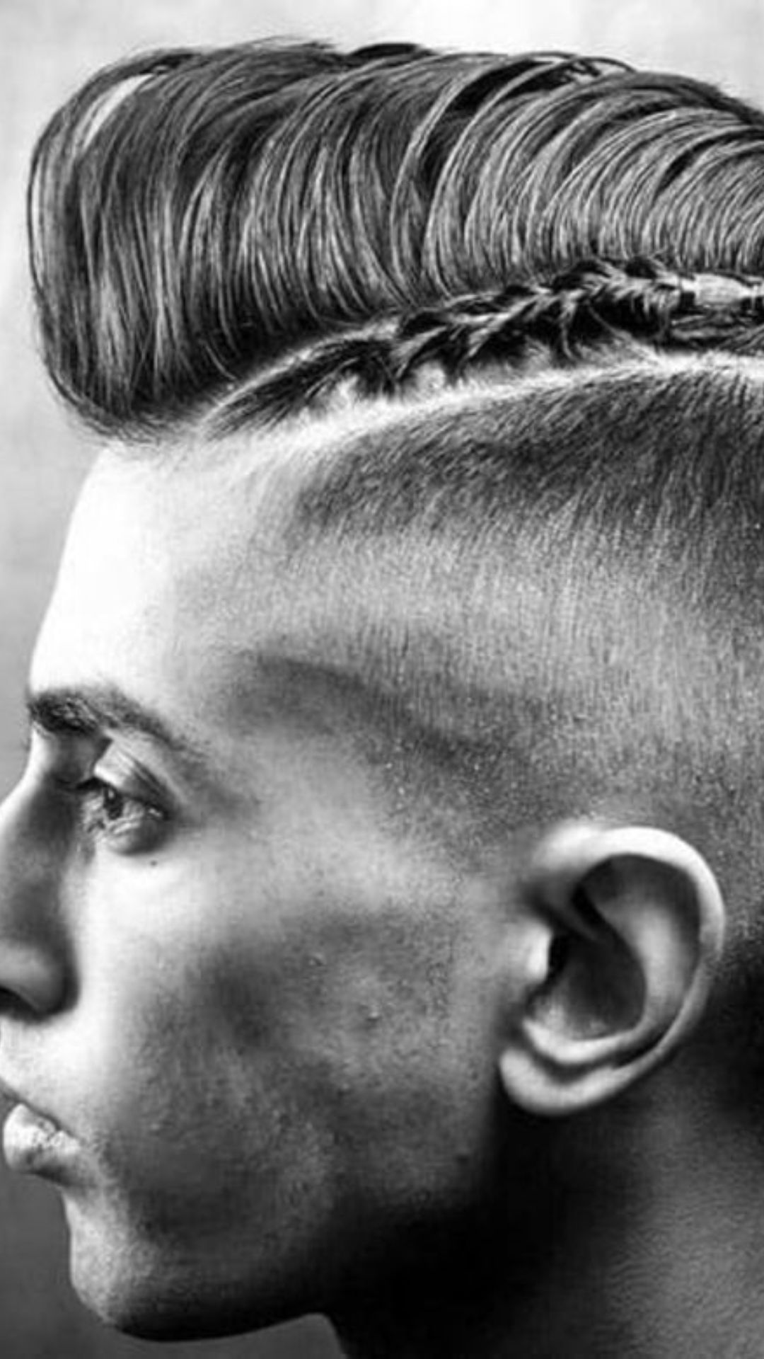 A man showcasing a bold mohawk hairstyle, complemented by intricate braid designs for a unique and striking look.