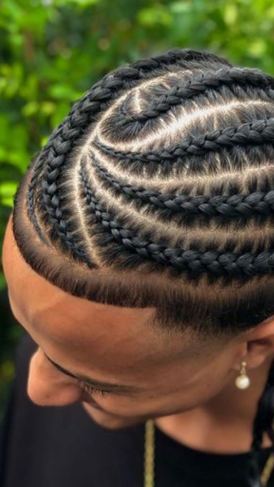 A man sporting a trendy braid hairstyle, characterized by numerous braids elegantly arranged on his head.