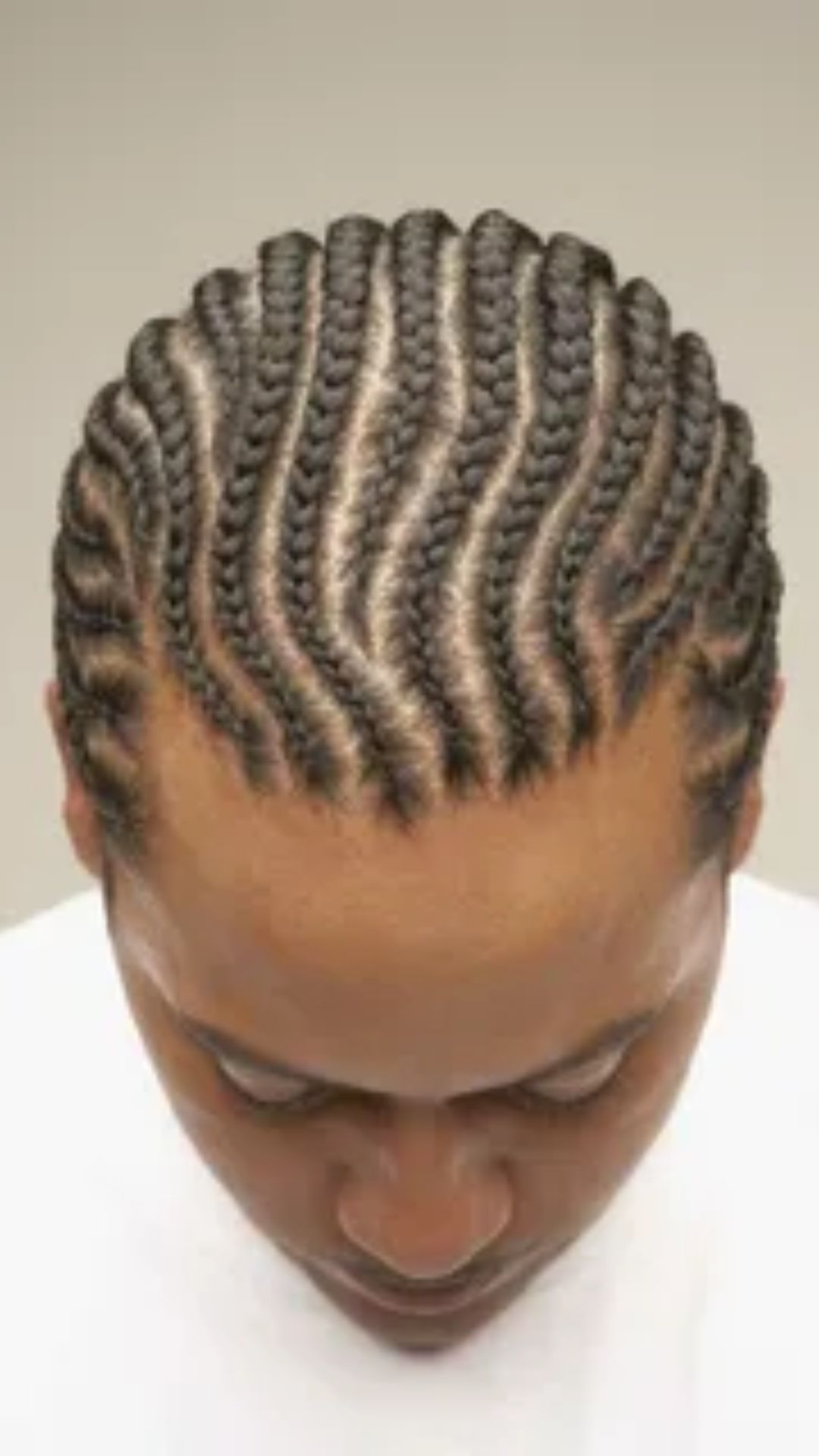 A man showcasing a stylish braided hairstyle, highlighting the intricate patterns of his hair.