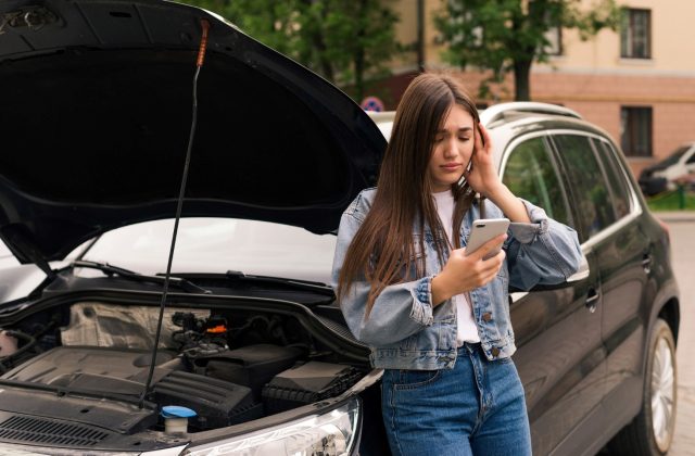 Young worried woman calling mechanic for help as her car having fuel system problem
