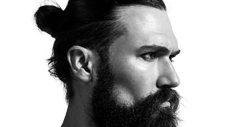 A man with a long beard and a bun hairstyle, showcasing a blend of short and long hair features.